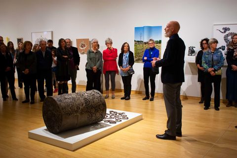 man explains sculpture piece to audience