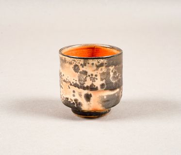 Spotted grey ceramic tea bowl with orange interior