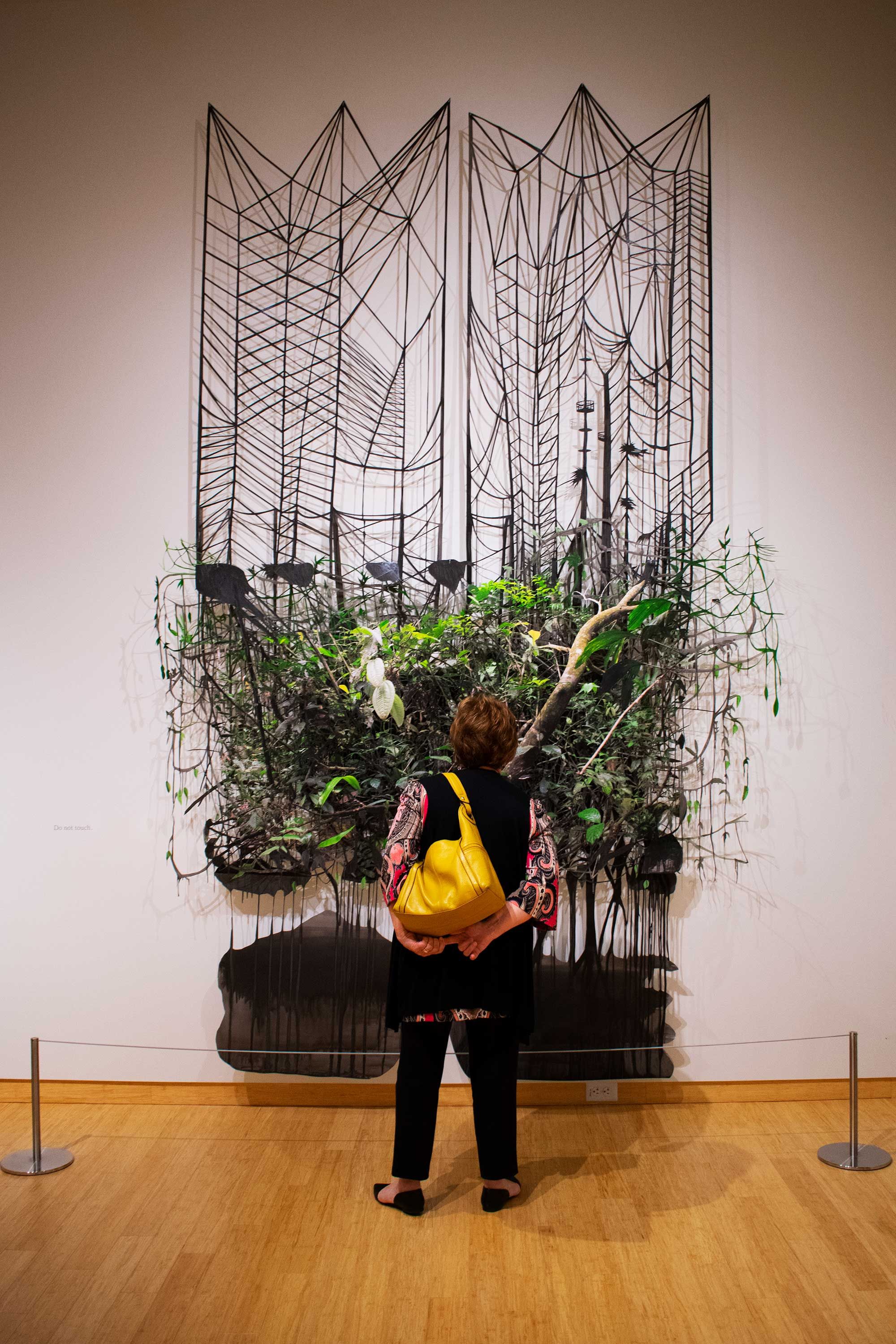 woman stands in front of art wth plants