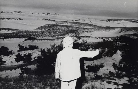 Black and white photograph of two people overlooking sand dunes
